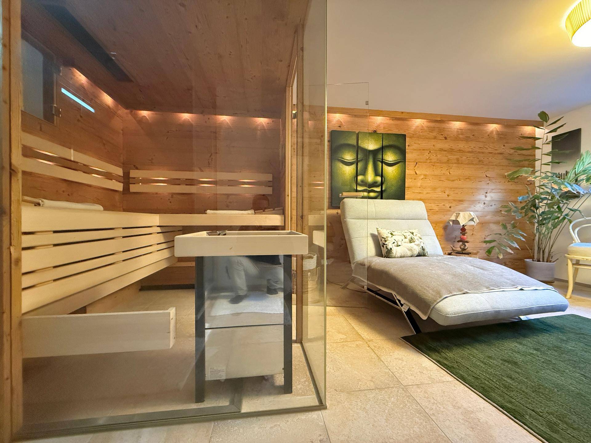 Entspannender Wellnessbereich mit moderner Sauna, Liege und Holzvertäfelung.