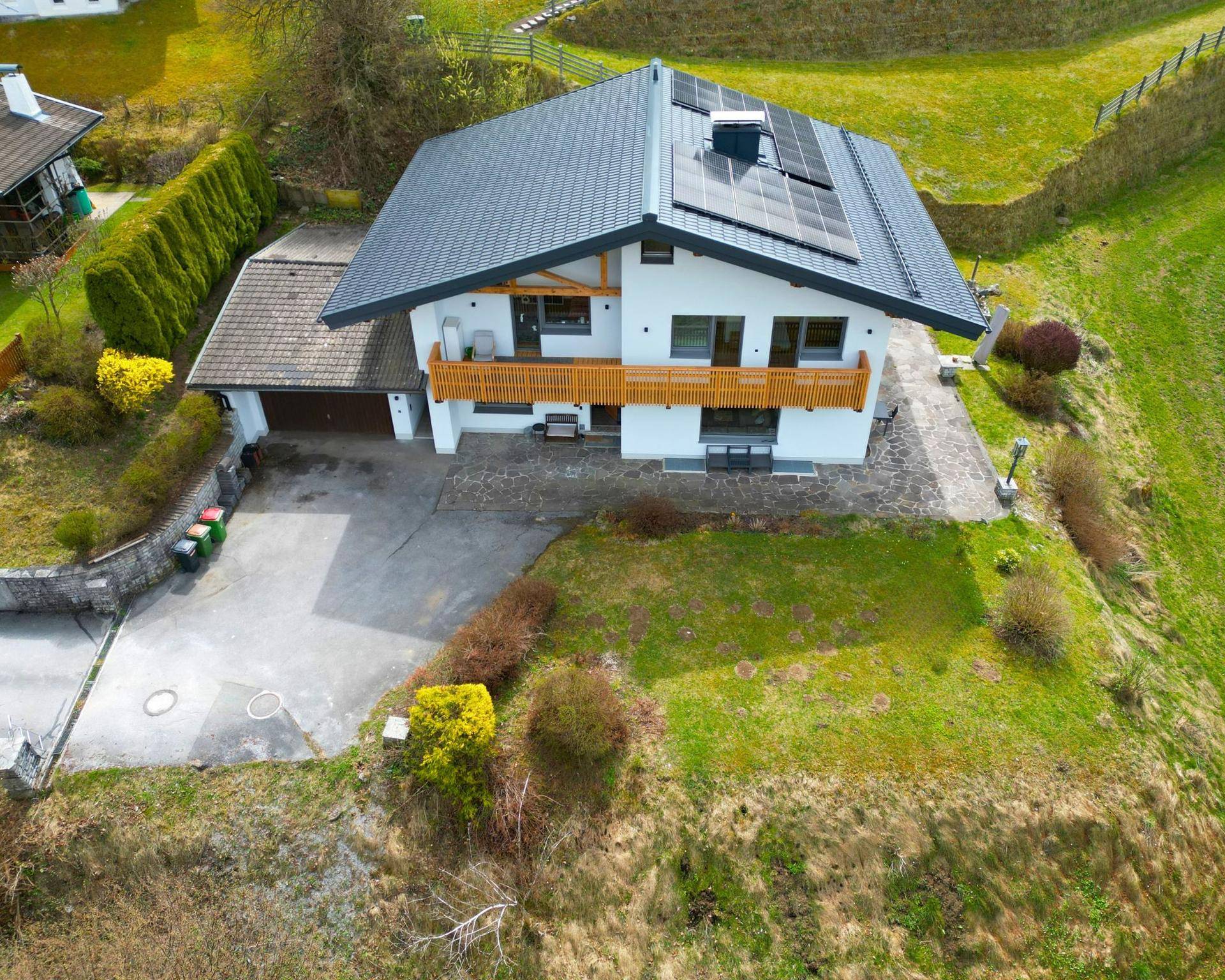Luftaufnahme eines Hauses mit Doppelgarage, Solaranlage und großem Gartenbereich.