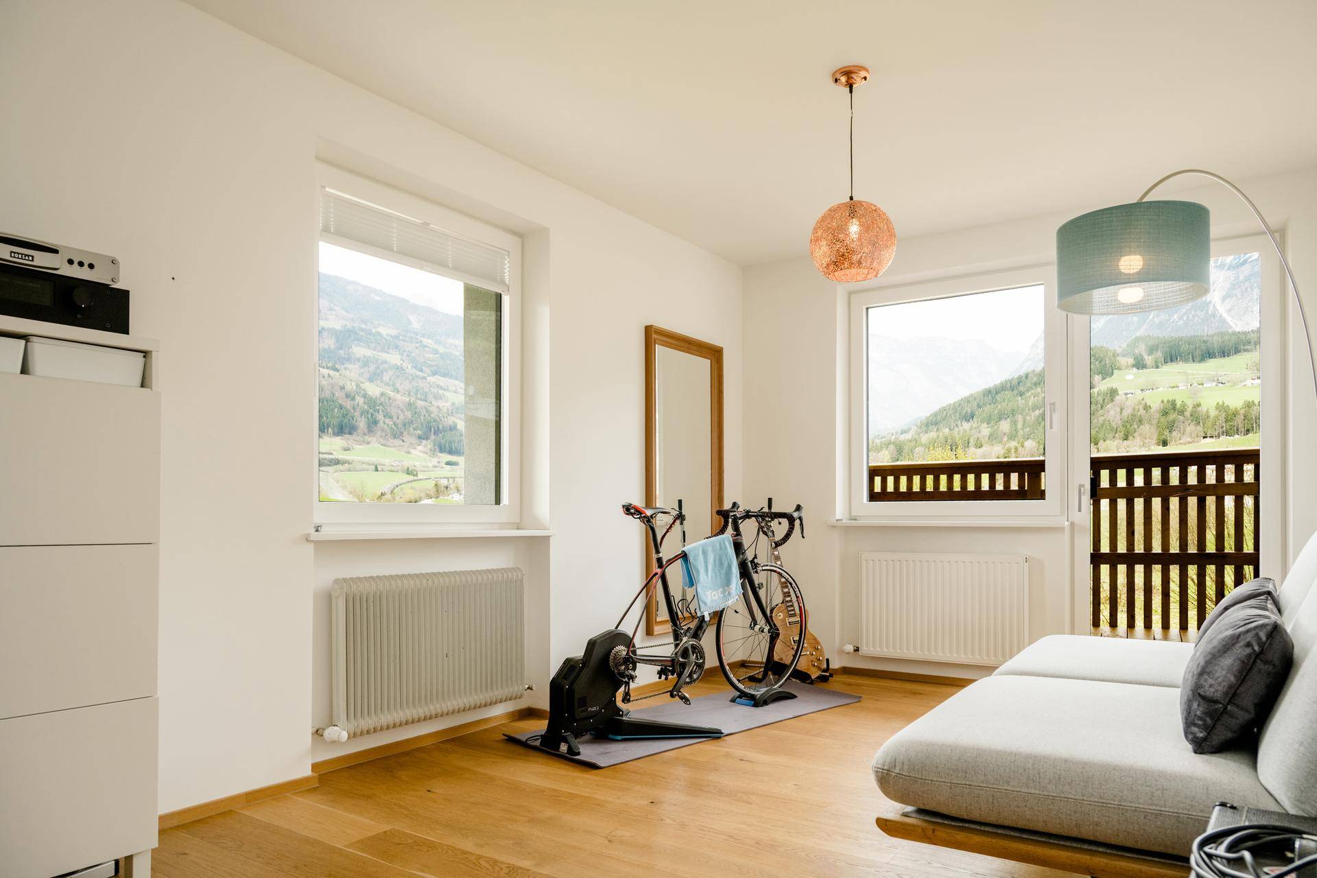 Helles Zimmer mit Holzboden, großem Fenster und Balkonzugang, genutzt als Fitness- und Gästezimmer.