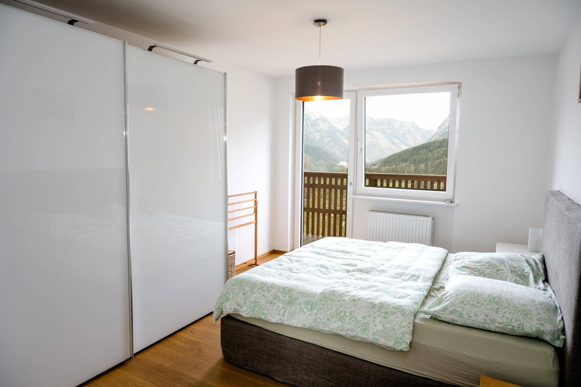 Gemütliches Schlafzimmer mit Doppelbett, Einbauschrank und Balkonzugang mit Bergblick.