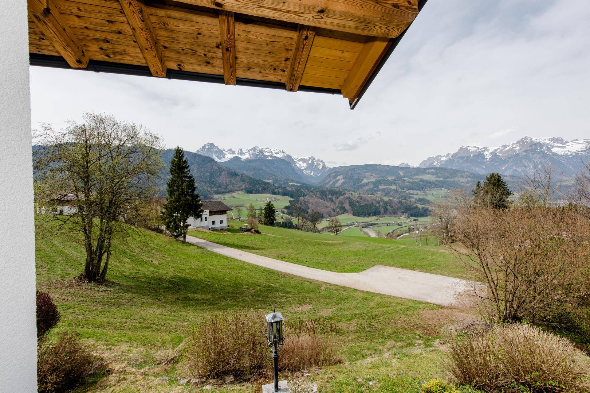 Malerischer Ausblick auf grüne Hügel, Wälder und schneebedeckte Berge in der Ferne.