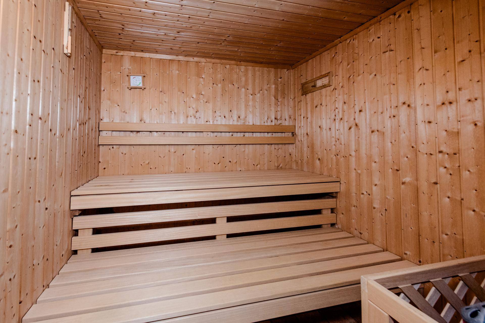 Geräumige Holzsauna mit mehrstufigen Bänken und traditionellem Saunaofen für Entspannung.
