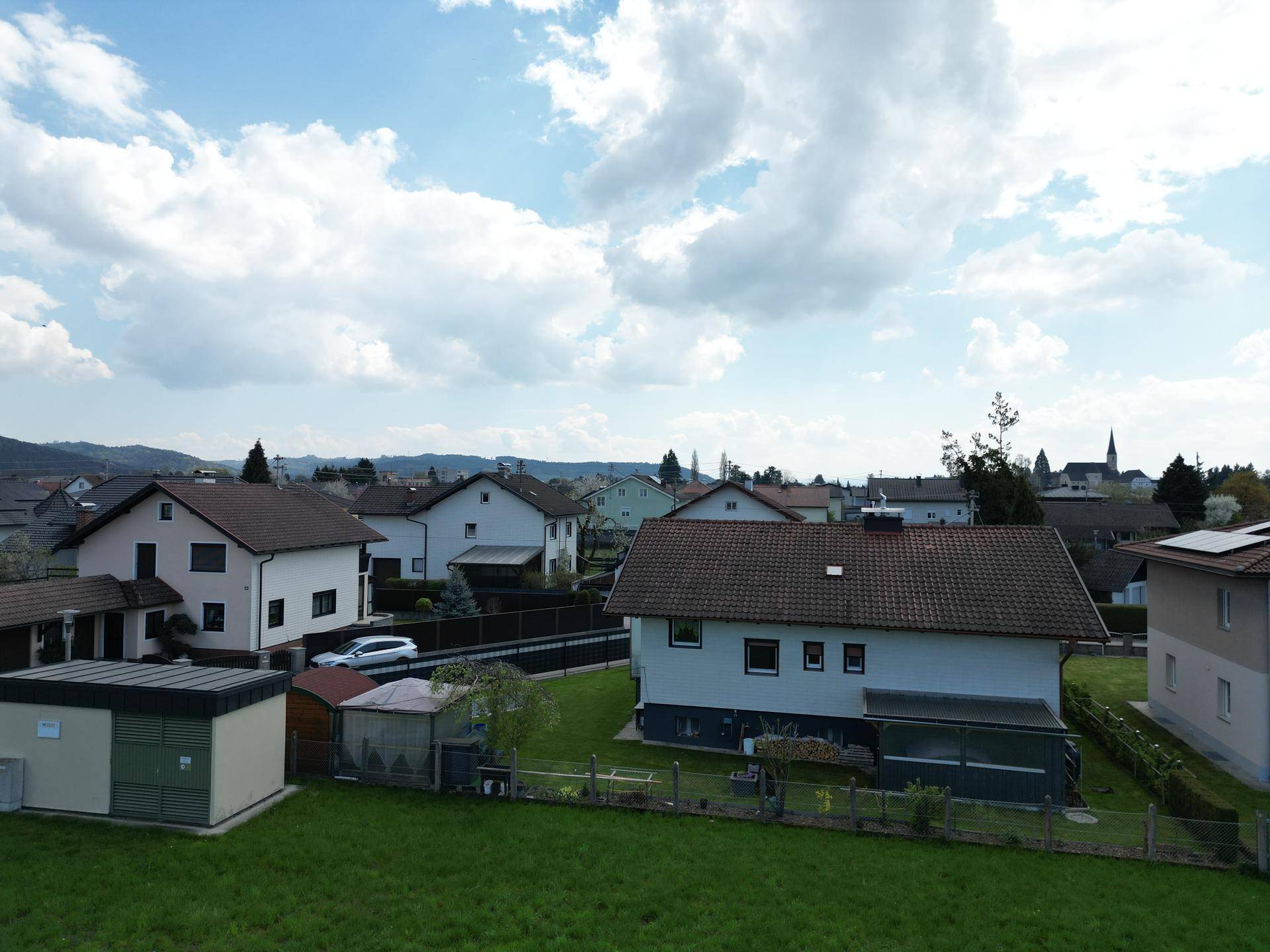 Luftaufnahme einer Wohnsiedlung mit Einfamilienhäusern, Gärten und einem Schuppen.