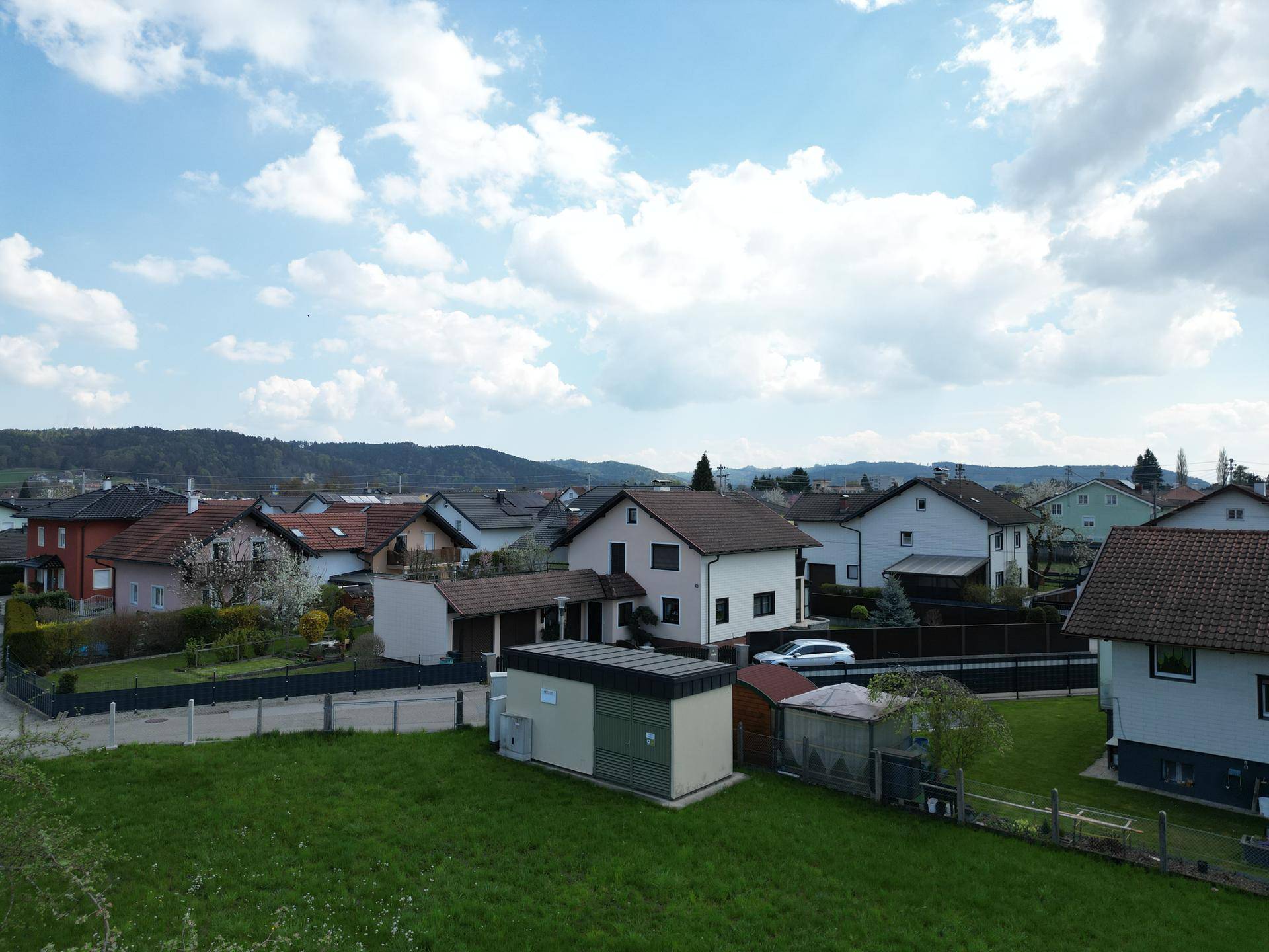 Luftaufnahme einer Wohngegend mit verschiedenen Häusern, Gärten und einem Schuppen.
