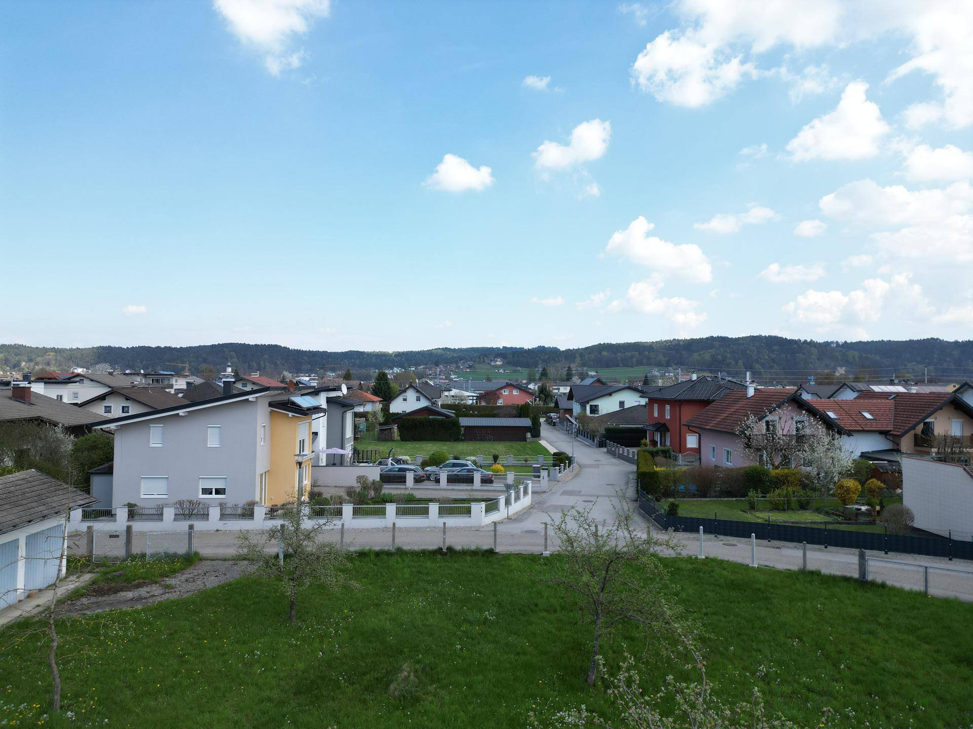 Weitläufige Luftaufnahme einer Wohnsiedlung mit vielen Häusern und grünen Gärten.