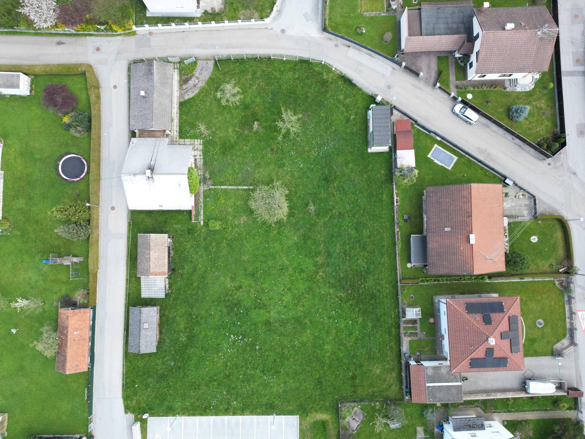 Vogelperspektive eines weitläufigen grünen Grundstücks mit umliegenden Häusern und Straßen.