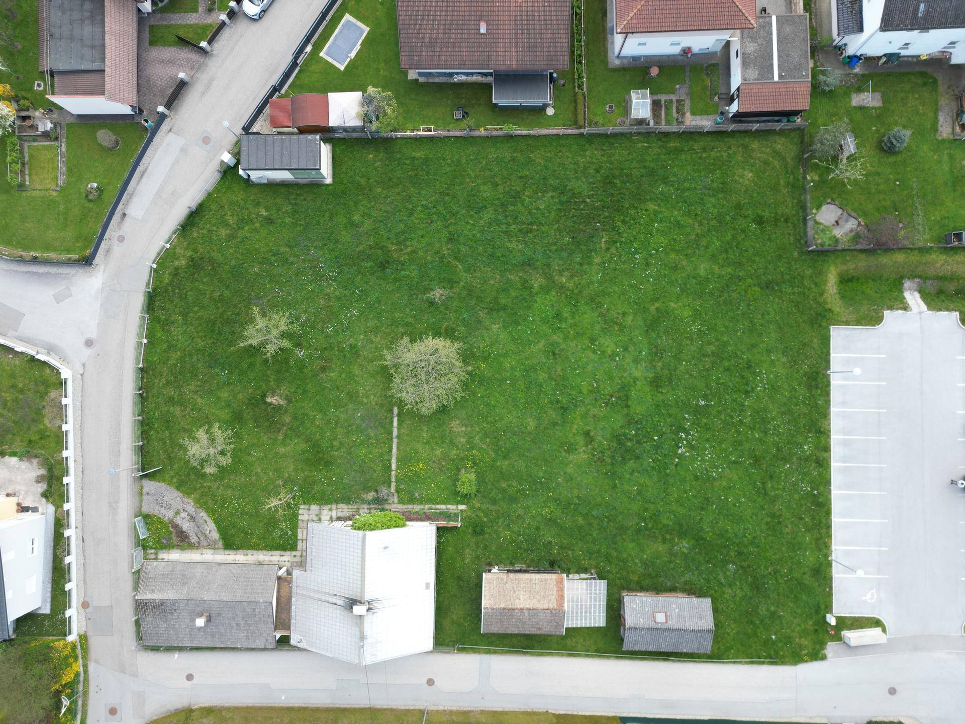 Senkrechte Luftaufnahme eines großen grünen Grundstücks mit angrenzenden Straßen und Gebäuden.