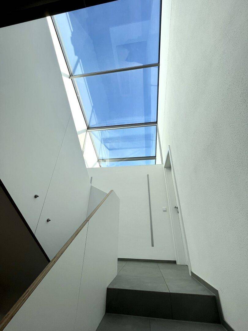 Moderner Treppenbereich mit viel Tageslicht durch die große Dachverglasung.