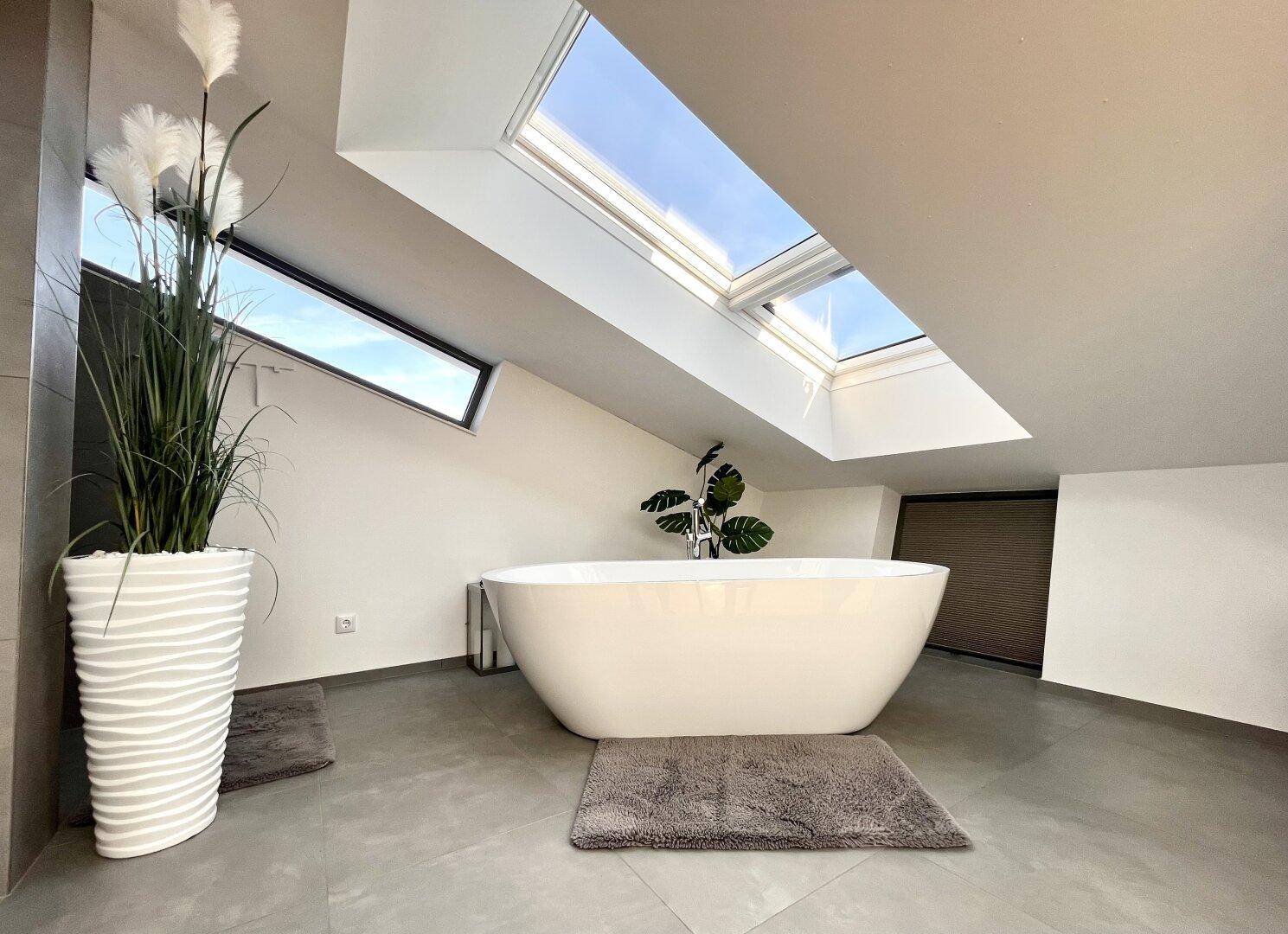 Geräumiges Badezimmer mit freistehender Badewanne und Dachfenstern für natürliches Licht.
