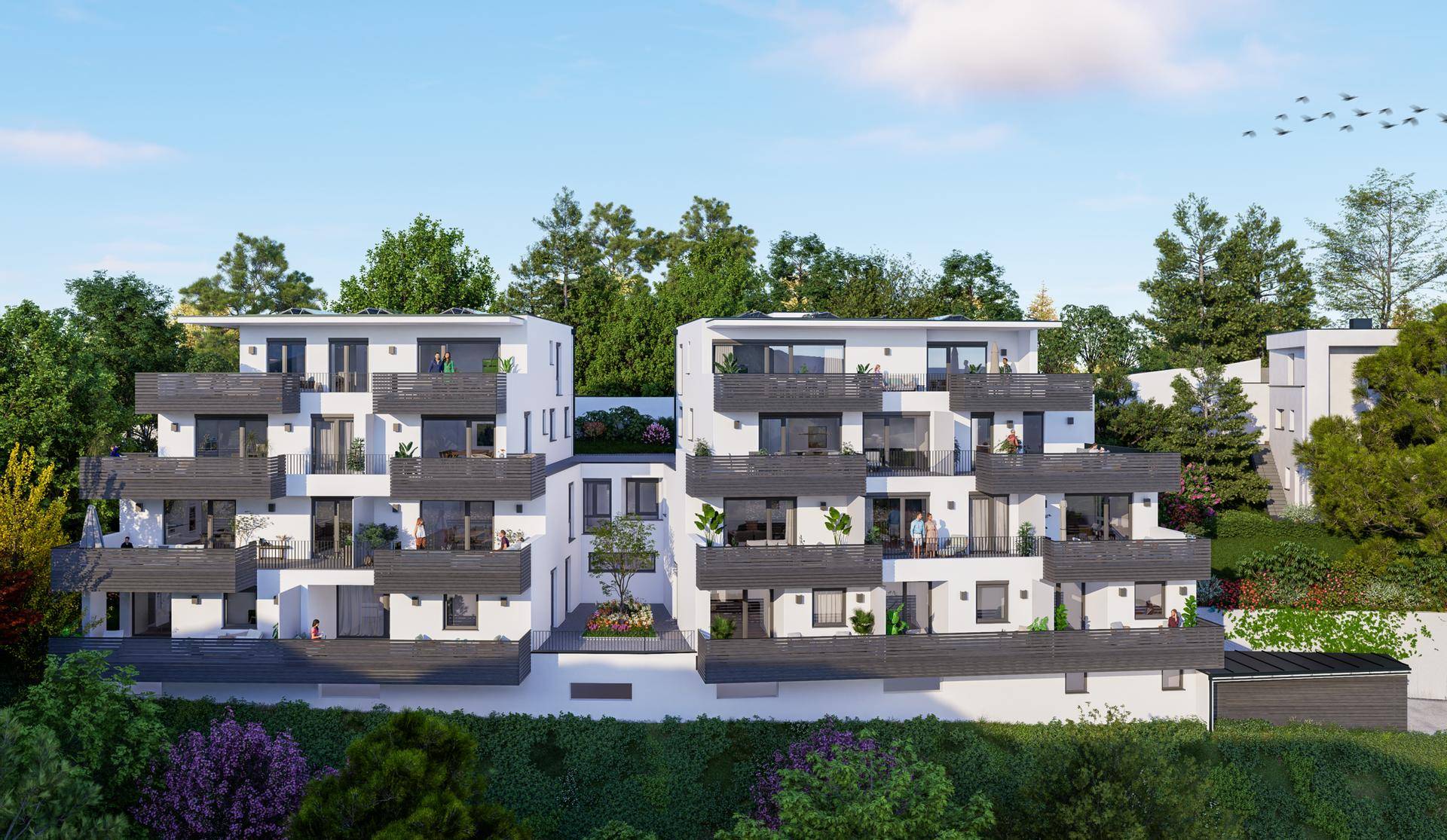 Moderne Wohngebäude mit Balkonen und Terrassen, eingebettet in eine grüne Umgebung mit Bäumen.