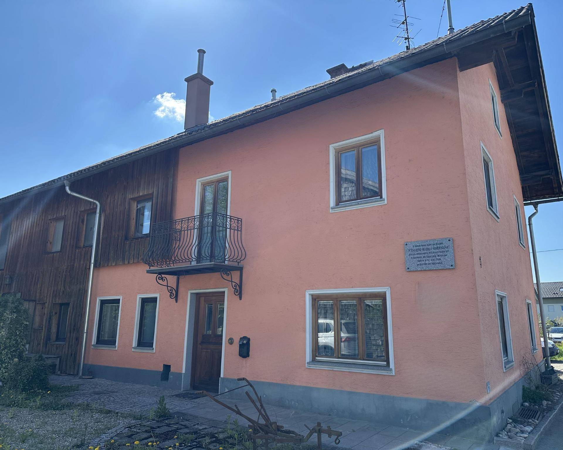 Traditionelles Wohnhaus mit rosafarbener Fassade, kleinen Fenstern und einem dekorativen französischen Balkon.