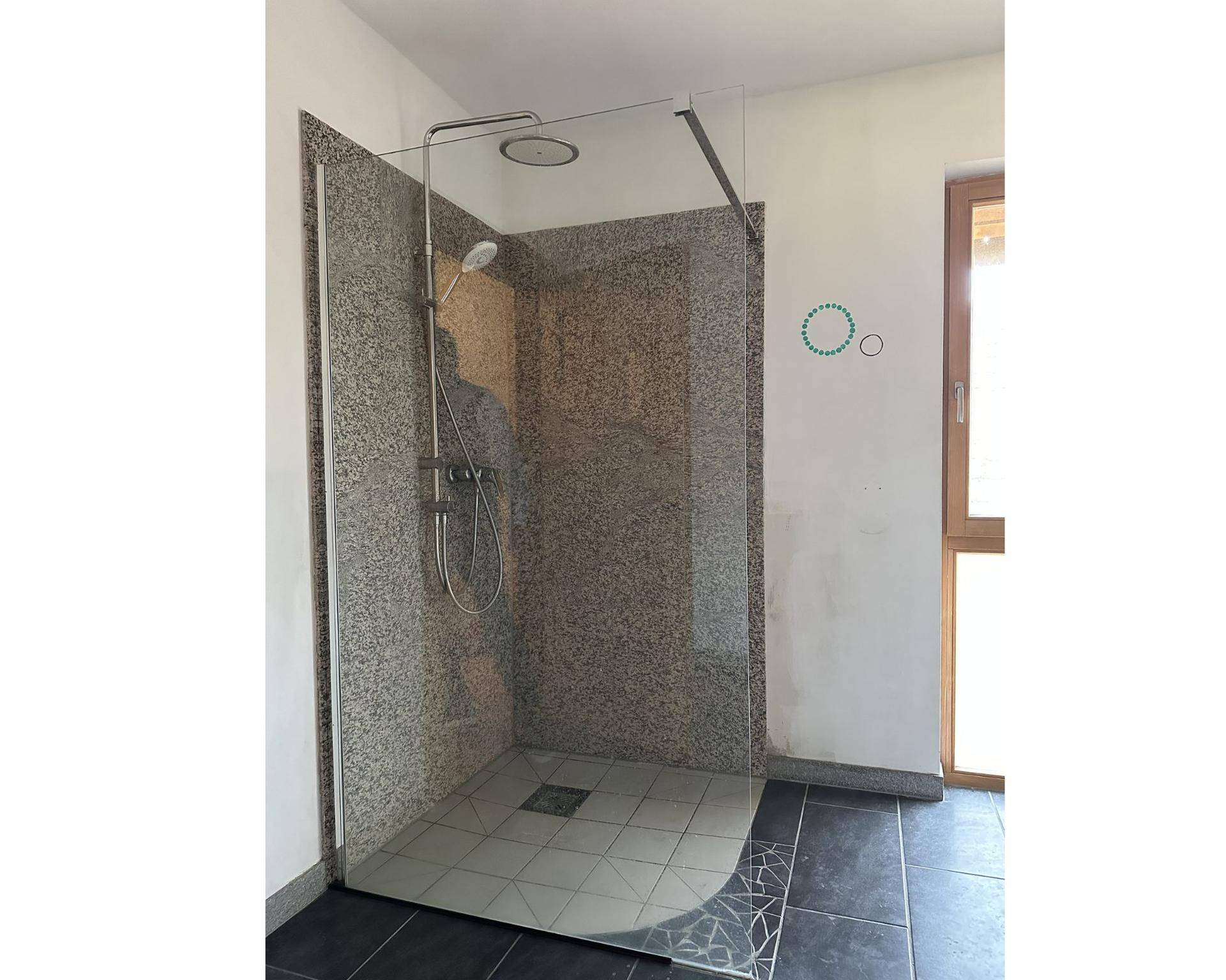 Modernes Badezimmer mit einer geräumigen begehbaren Dusche und dunklen Bodenfliesen.