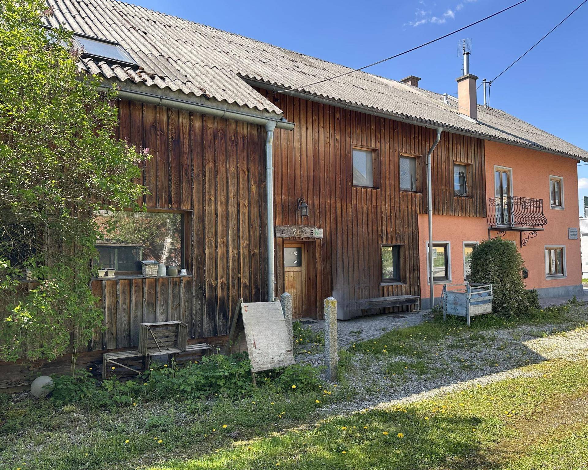 Gesamtansicht des Anwesens mit rosafarbenem Haupthaus und angrenzendem rustikalen Holzgebäude.