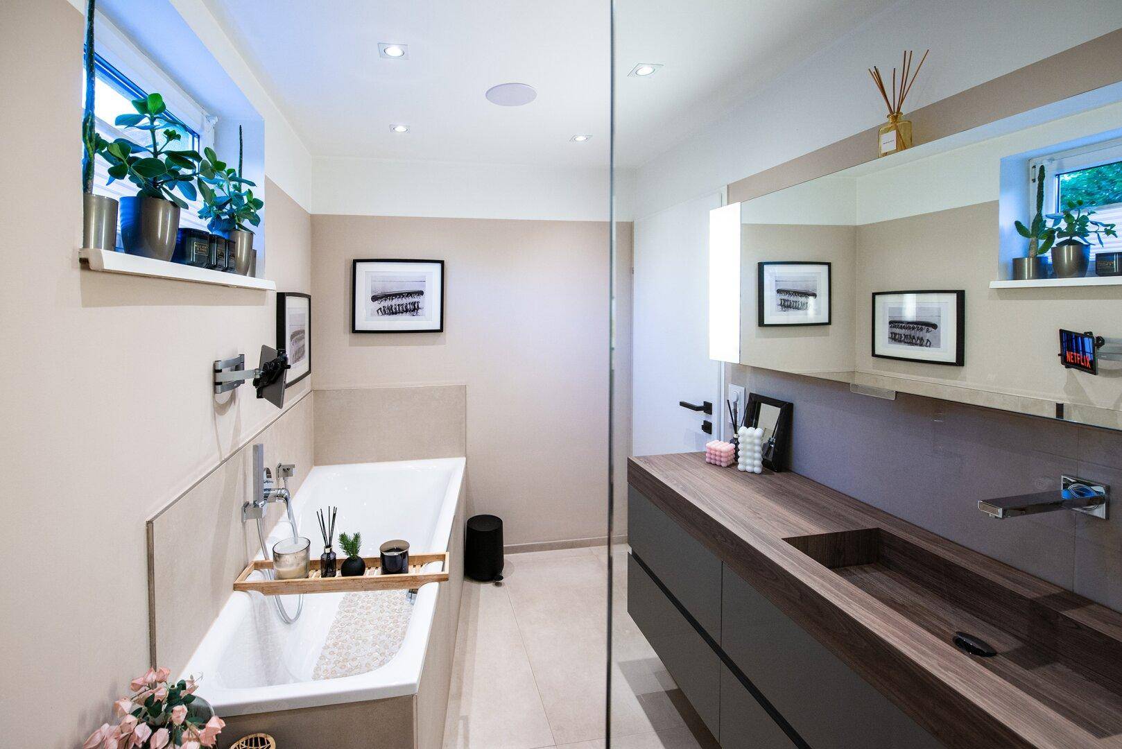 Elegantes Badezimmer mit Badewanne, Doppelwaschbecken und großem Spiegel, hell durch Fenster.