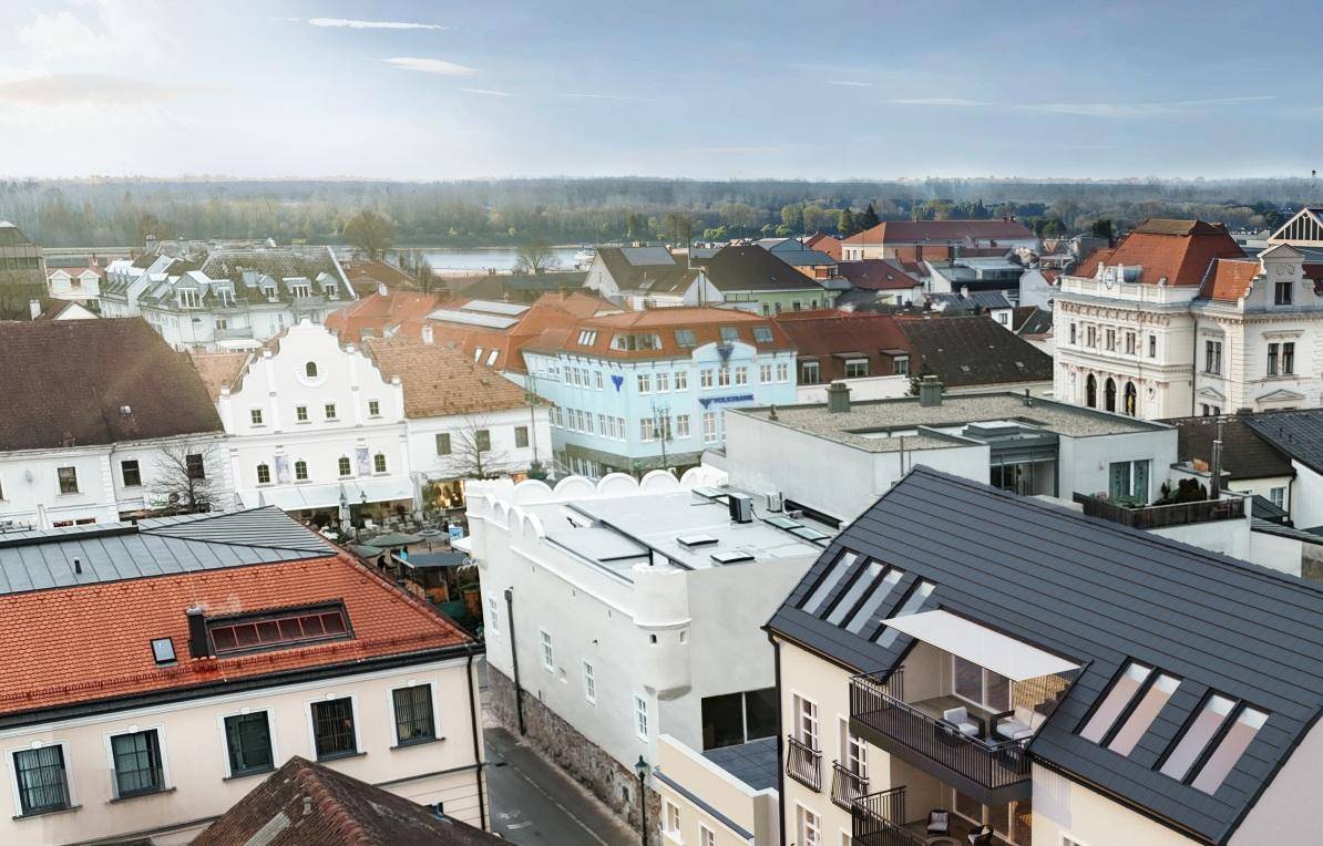 Luftaufnahme einer historischen Stadt mit vielfältiger Architektur und Blick auf die umliegende Landschaft und einen See.