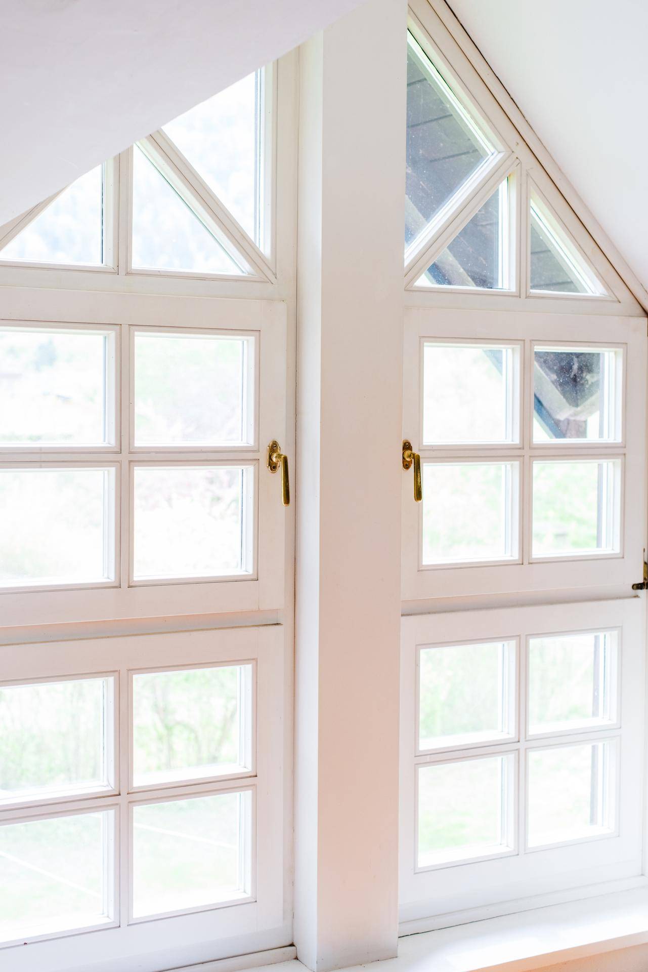 Große, helle Fenster mit Sprossen und dreieckigen Oberlichtern, die viel Tageslicht hereinlassen.
