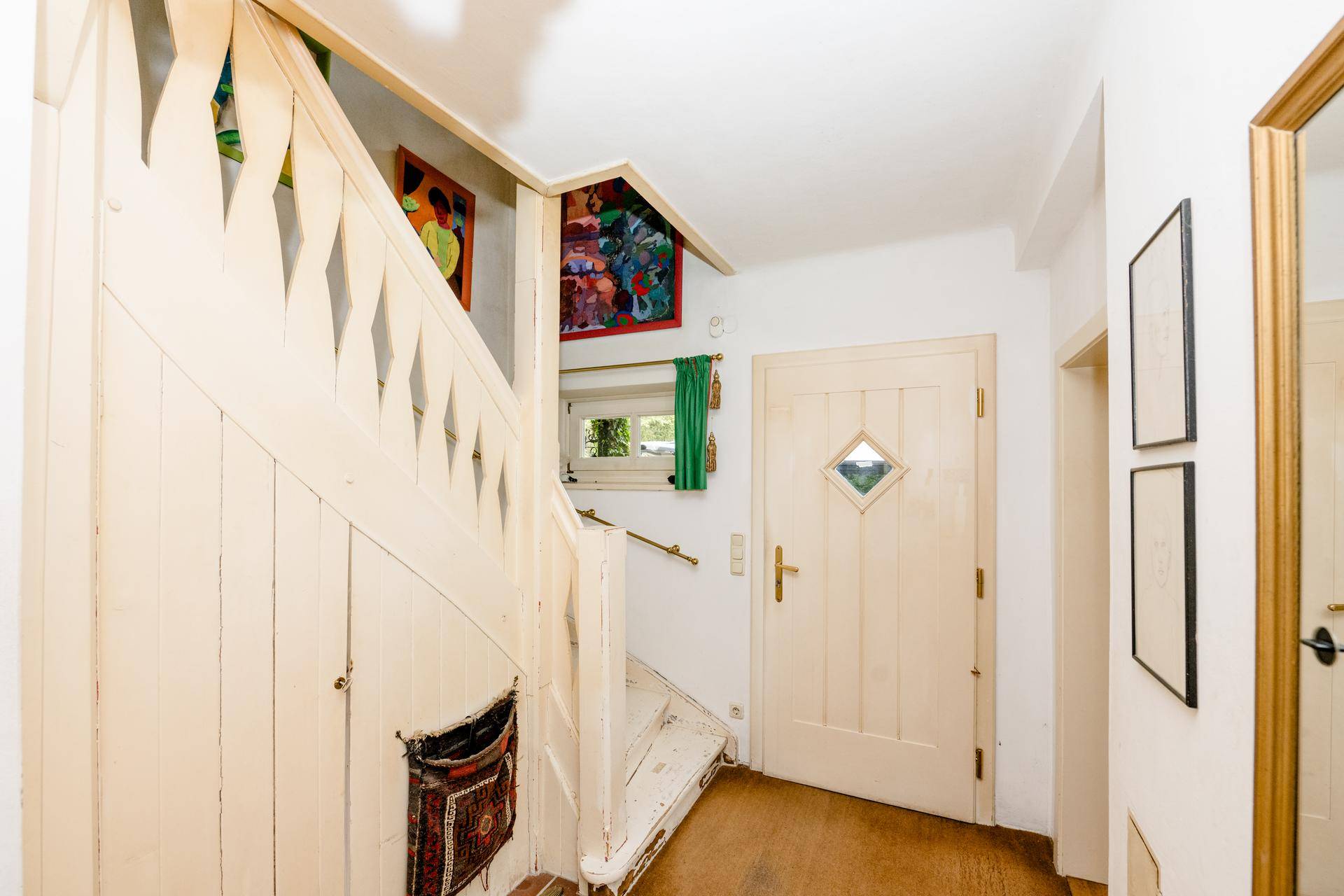 Heller Eingangsbereich mit Holztreppe und traditioneller Holztür.