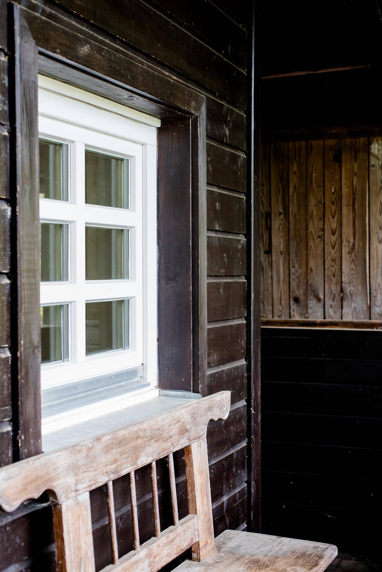 Detailaufnahme eines Fensters mit Holzrahmen in einer dunklen Holzfassade.