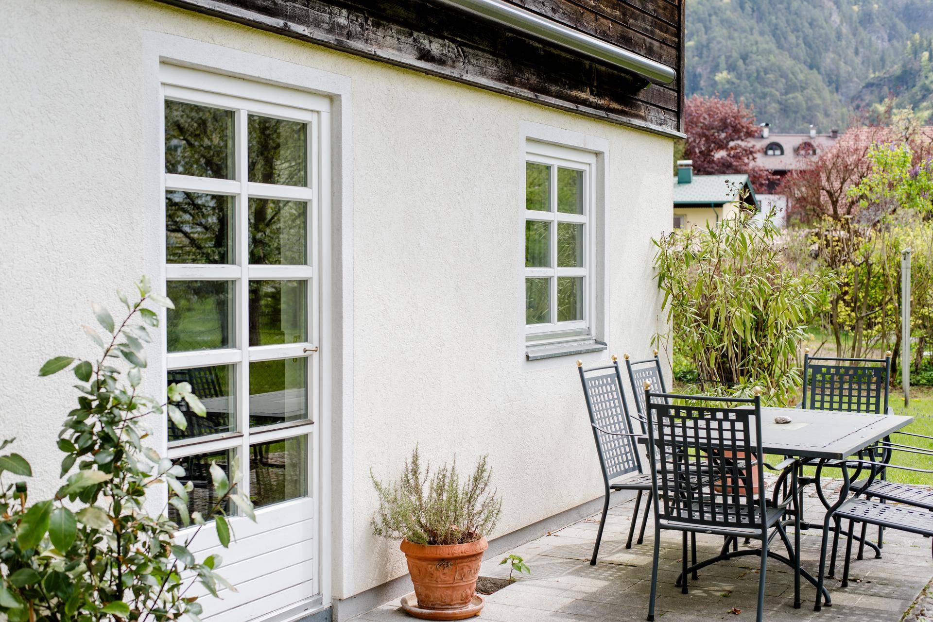 Gemütliche Terrasse mit Gartenmöbeln neben dem Haus, umgeben von grüner Vegetation.