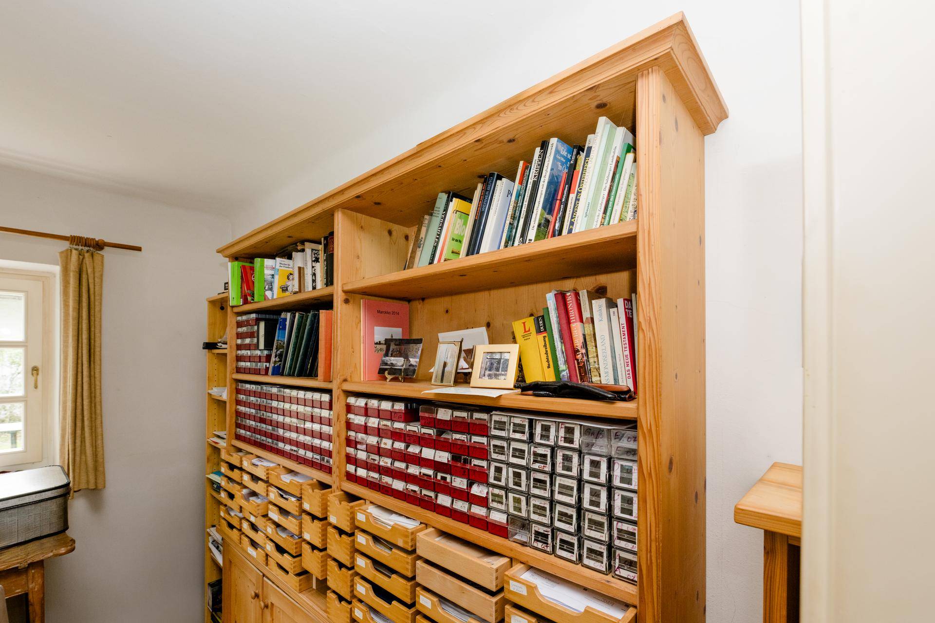 Großes Holzregal mit Büchern und vielen kleinen Schubladen, ideal für ein Arbeitszimmer.