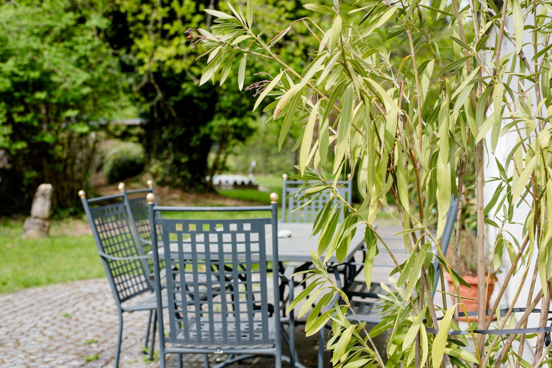 Gartenmöbel auf einer Terrasse, umgeben von grünen Pflanzen und Bäumen.