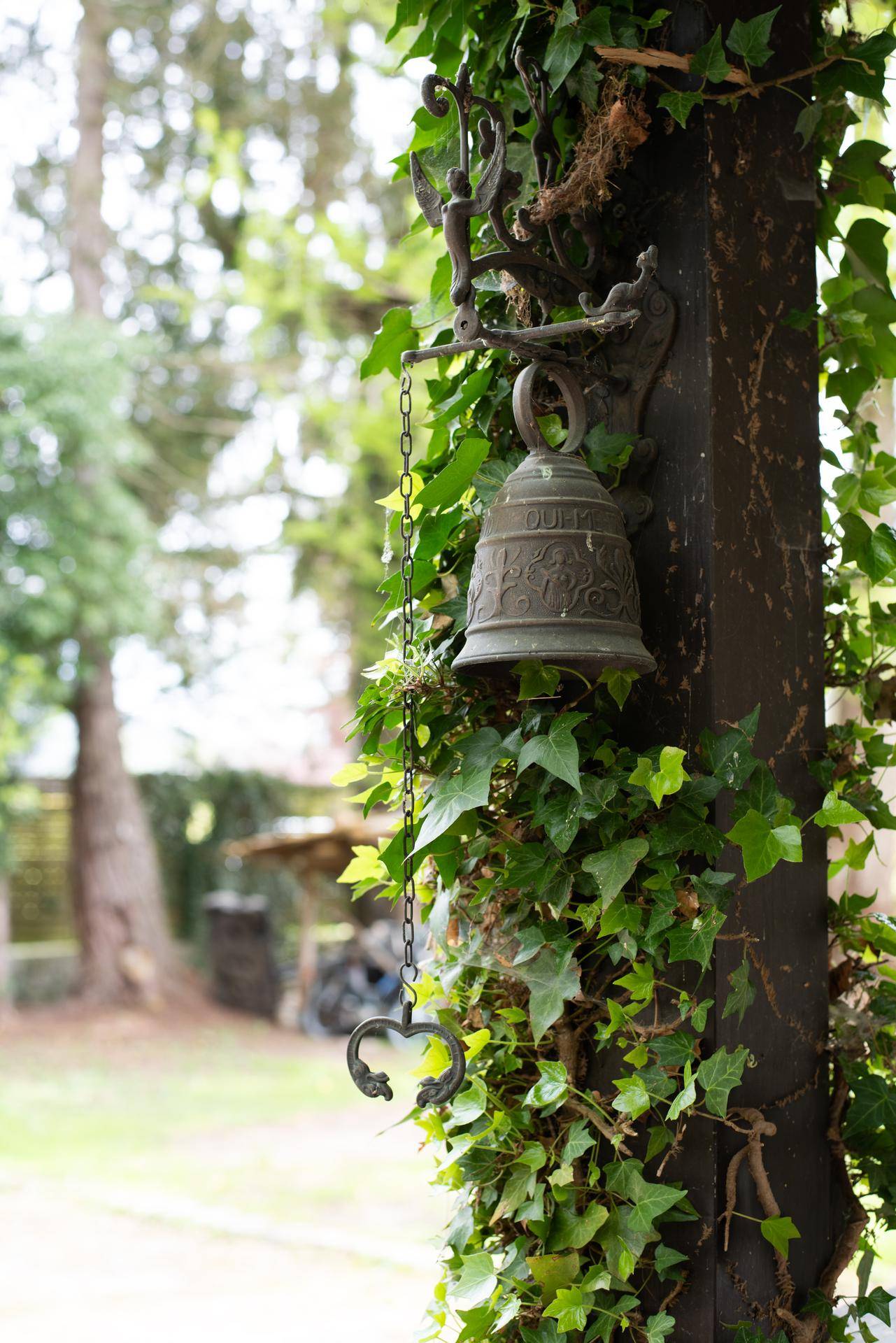 Eine alte Glocke, umrankt von Efeu, als dekoratives Element im Garten.