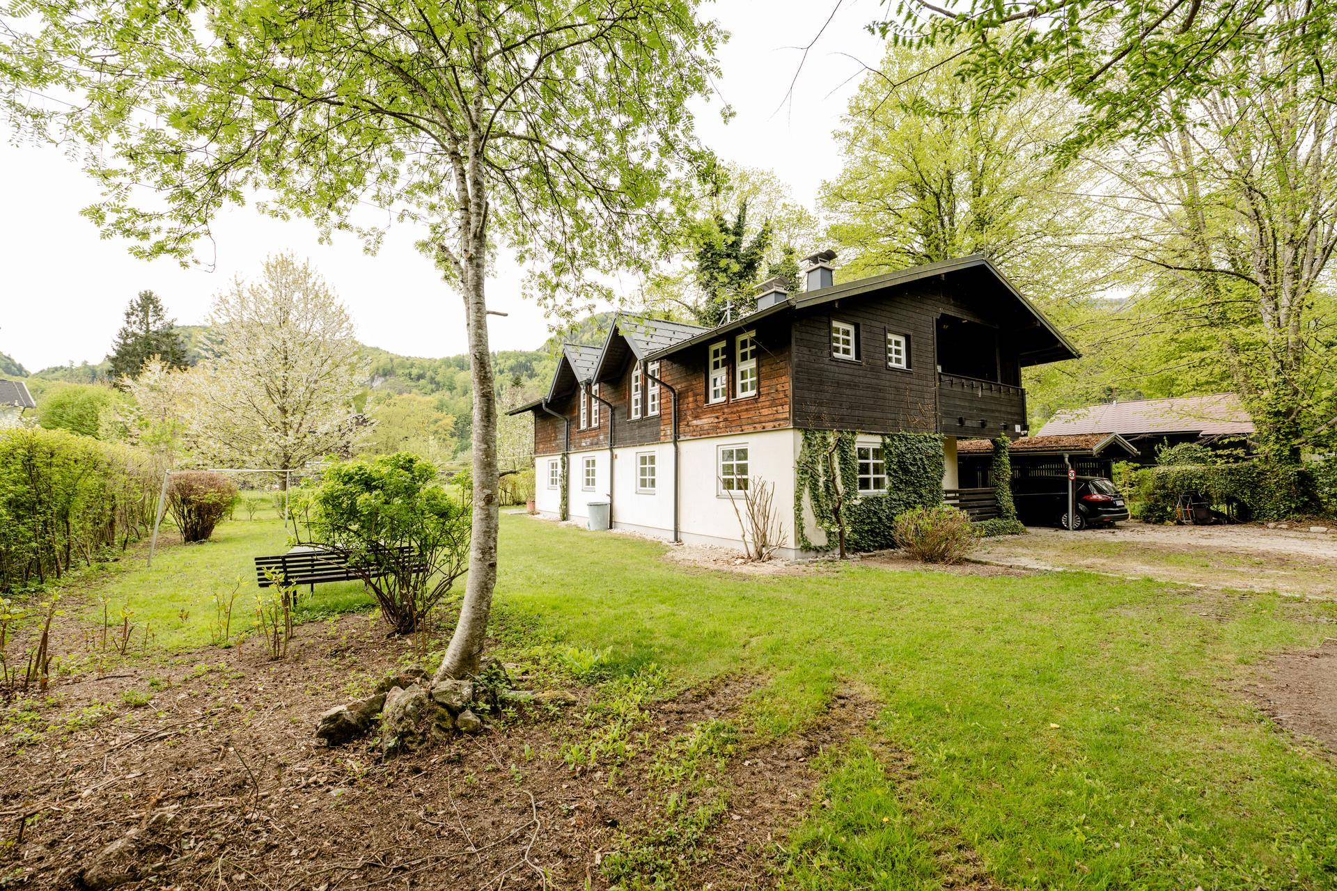 Charmantes Landhaus mit Holzfassade und großem Garten, umgeben von üppiger Natur.