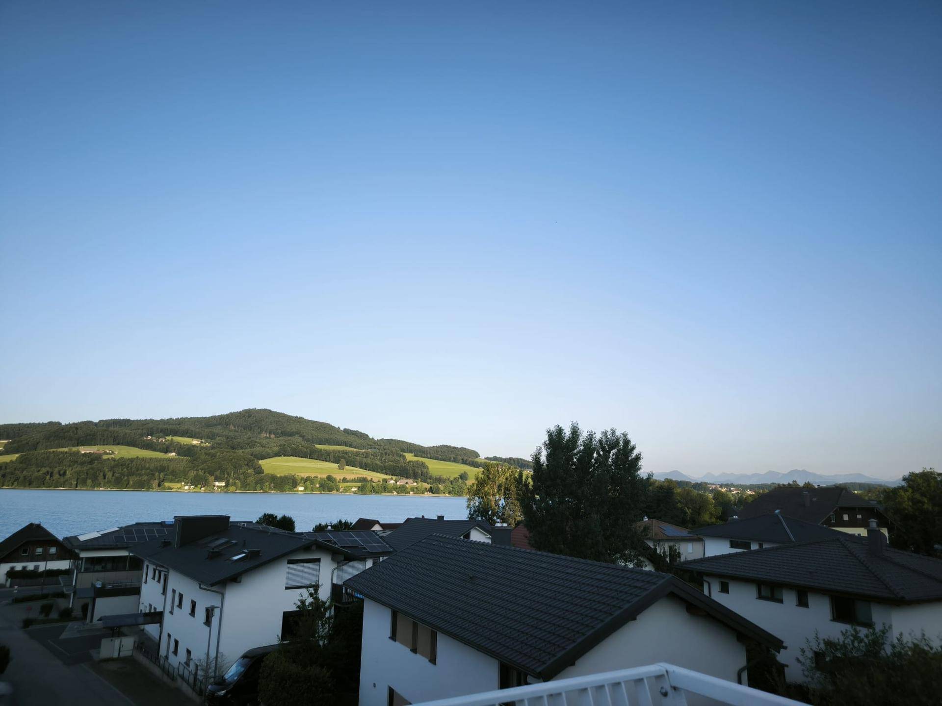 Weitläufiger Blick über den See und die umliegende grüne Landschaft an einem klaren Tag.