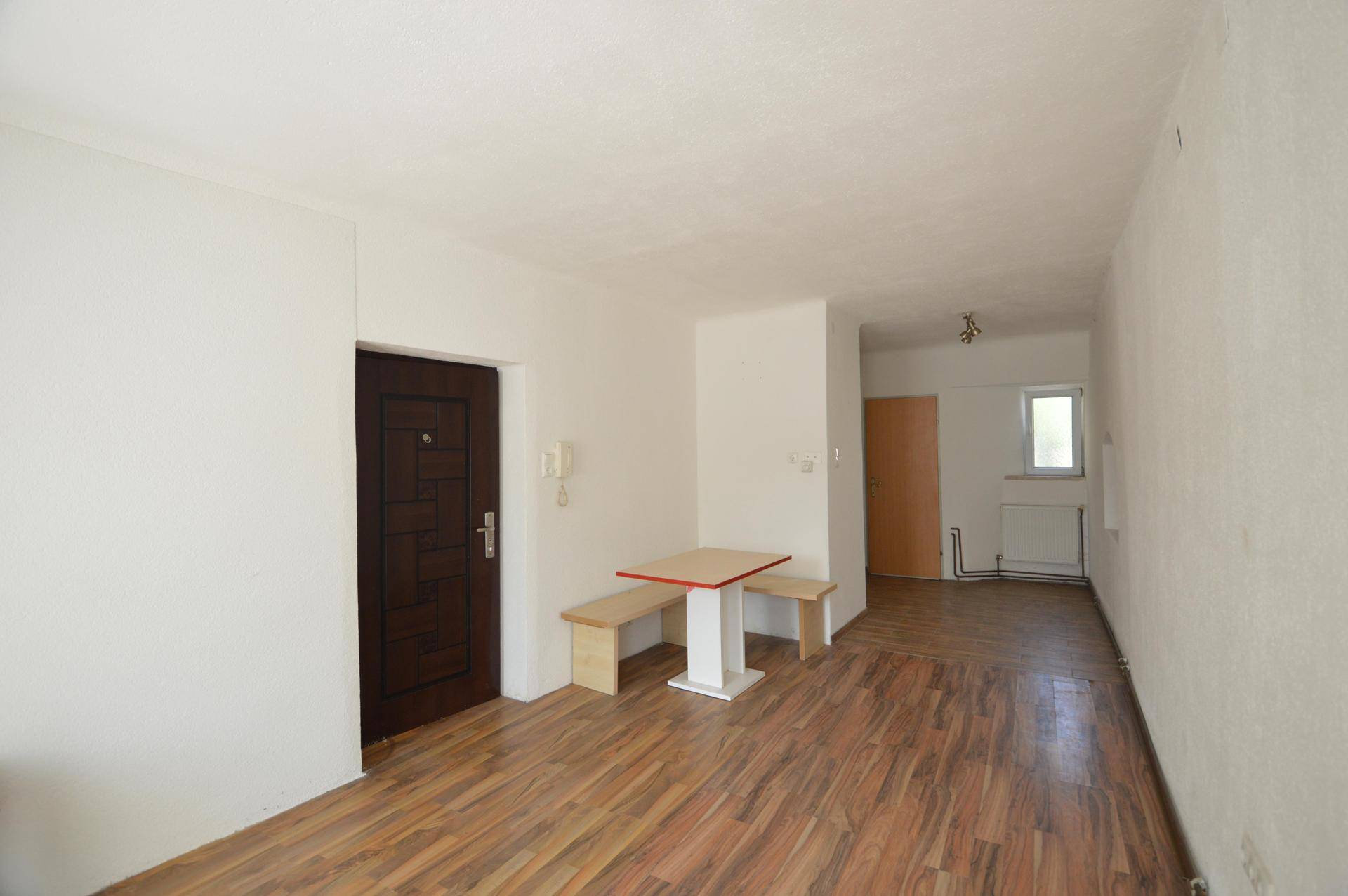 Geräumiger Raum mit Laminatboden und einem kleinen Esstisch, vielseitig nutzbar.