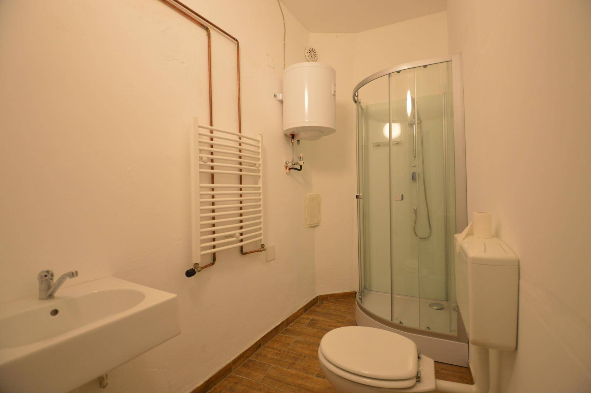Modernisiertes Badezimmer mit Duschkabine, Waschbecken und beheiztem Handtuchhalter.