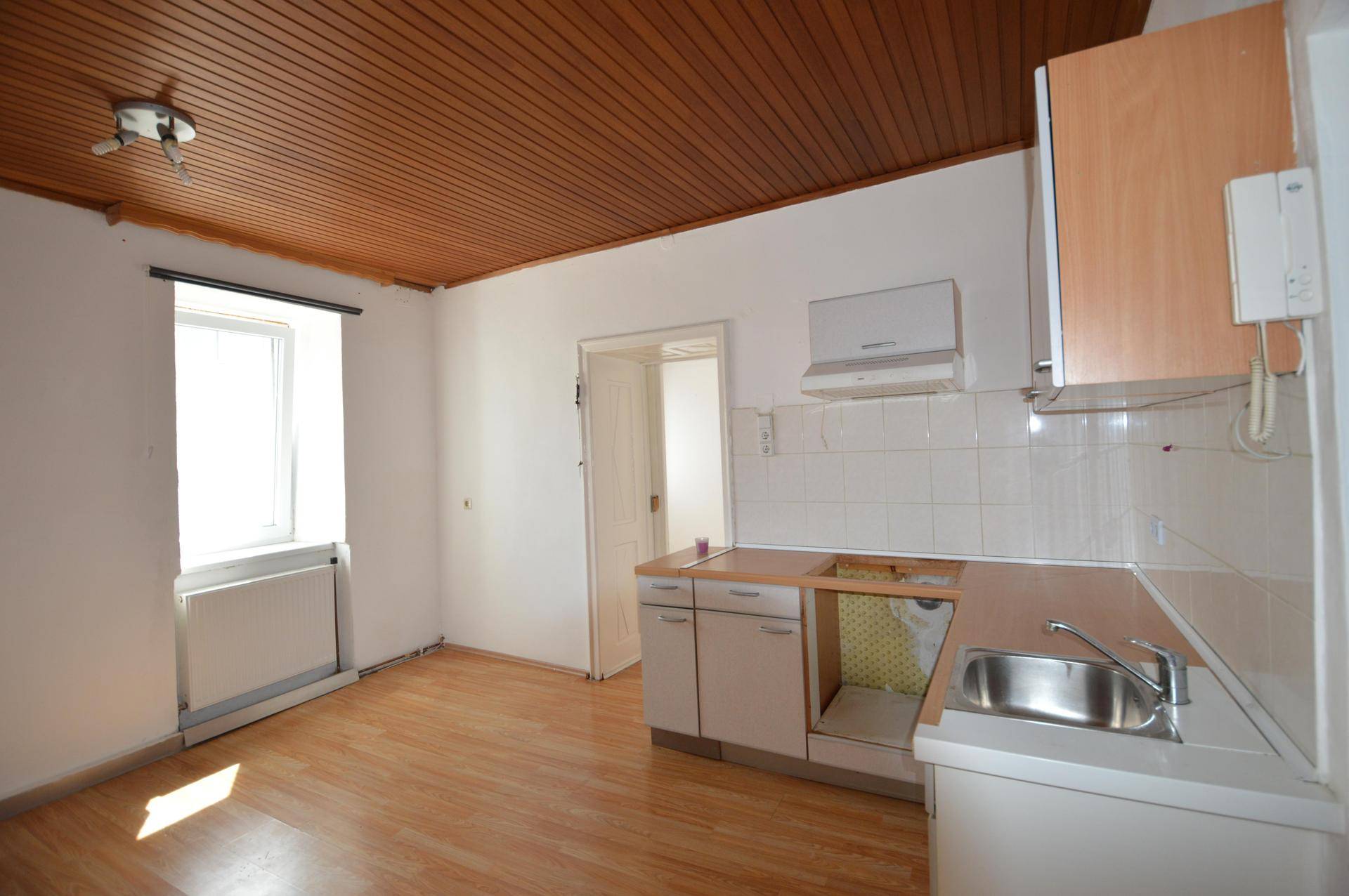 Küche mit Holzdecke und teilweise demontierter Einbauküche, bereit für eine Modernisierung.