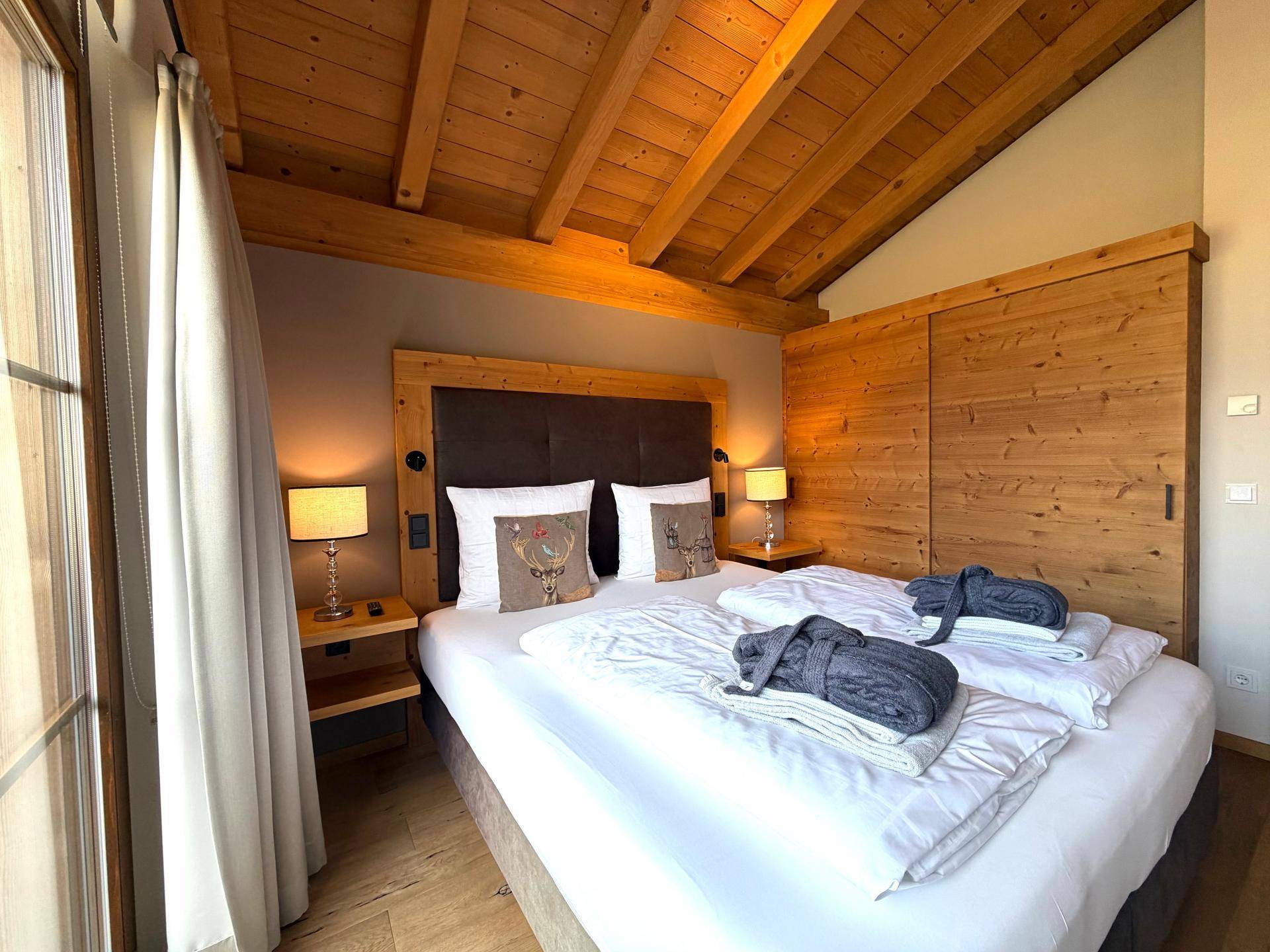 Gemütliches Schlafzimmer mit Holzbalkendecke, Doppelbett und integrierten Holzschränken.