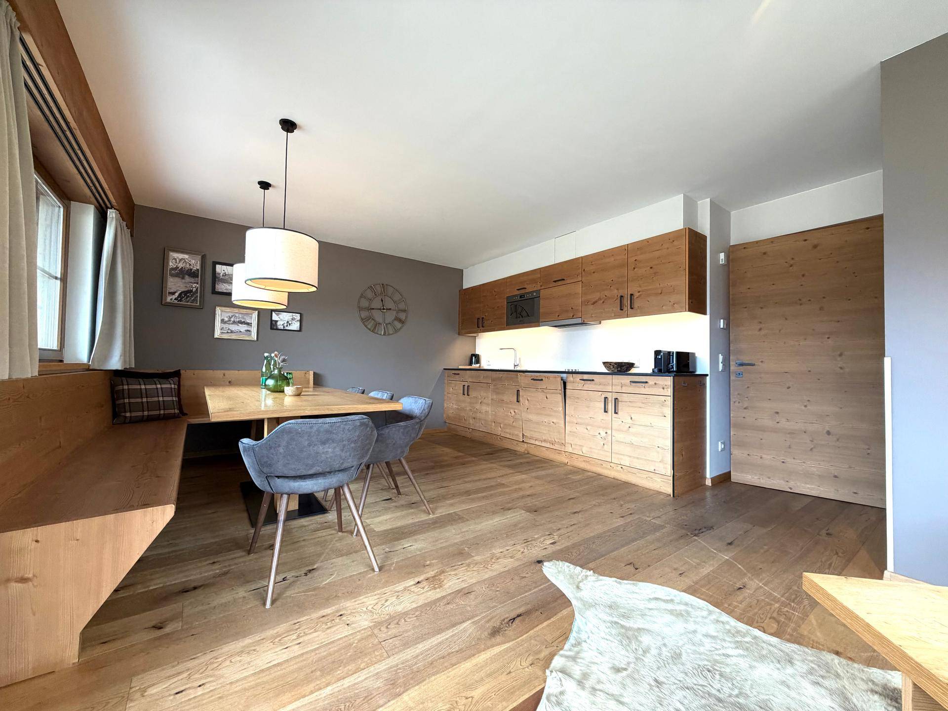Gemütlicher Wohn-Essbereich mit Holzküche, Eckbank und modernem Design in warmen Tönen.