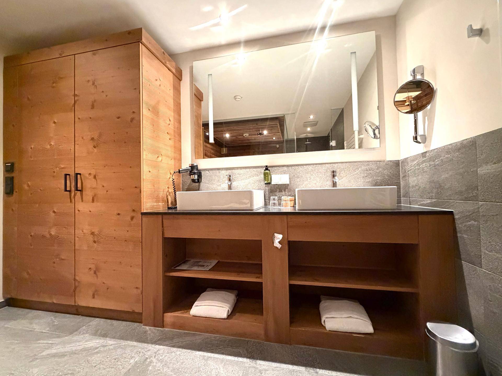 Modernes Badezimmer mit Doppelwaschbecken, großem Spiegel und Holzschrank.