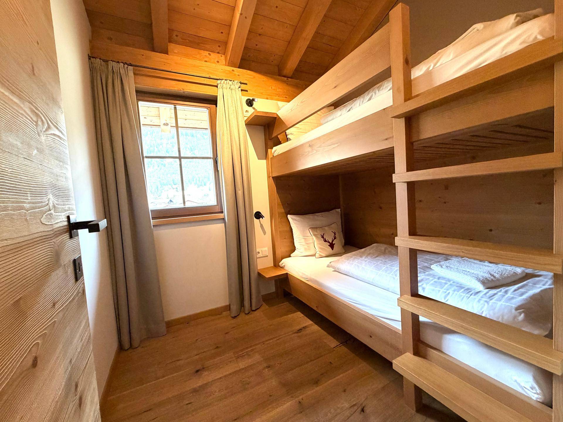 Kleines Schlafzimmer mit Etagenbett, Holzboden und Fenster in rustikalem Stil.