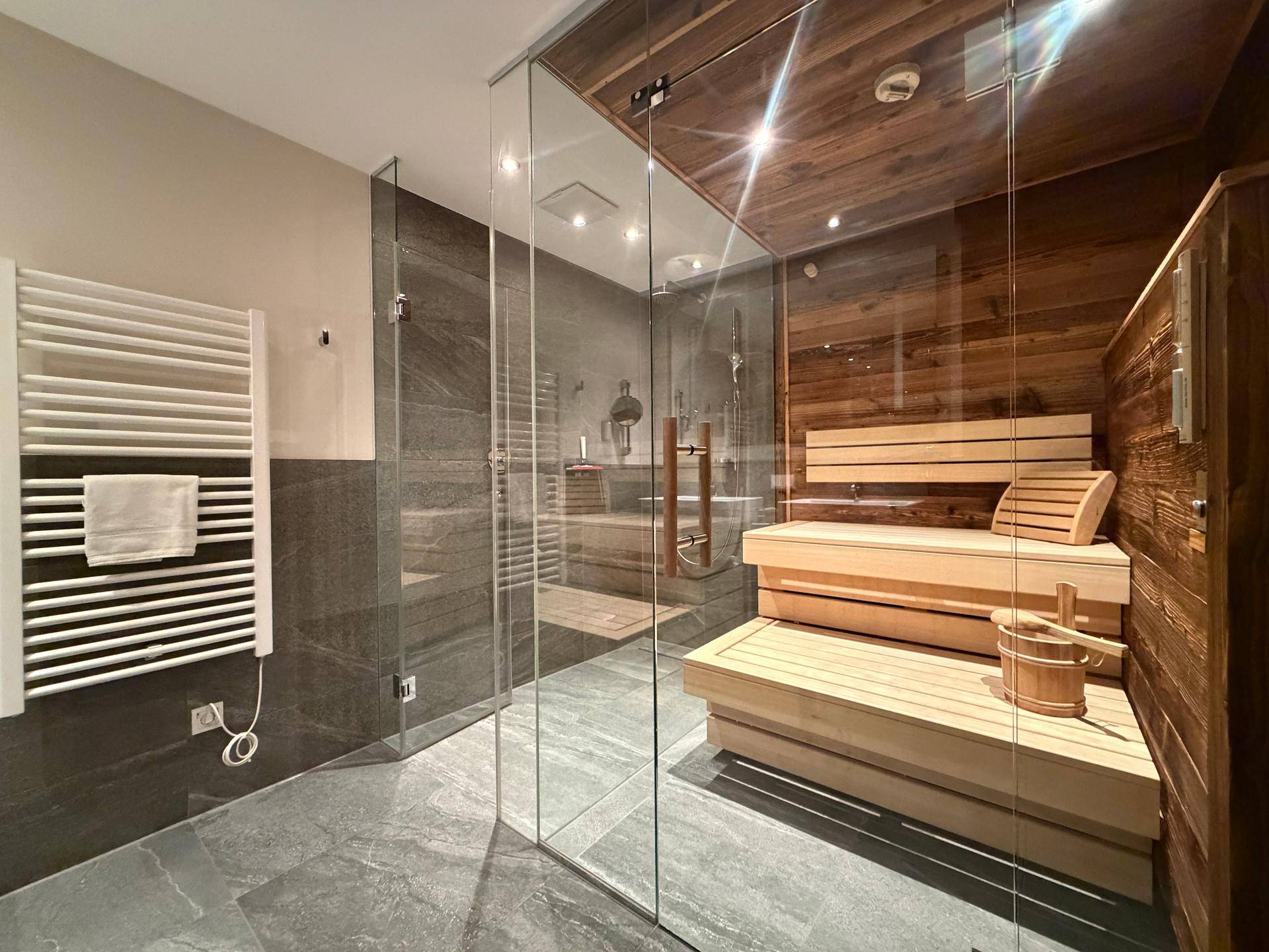 Modernes Badezimmer mit begehbarer Dusche und integrierter Sauna für Wellnessmomente.
