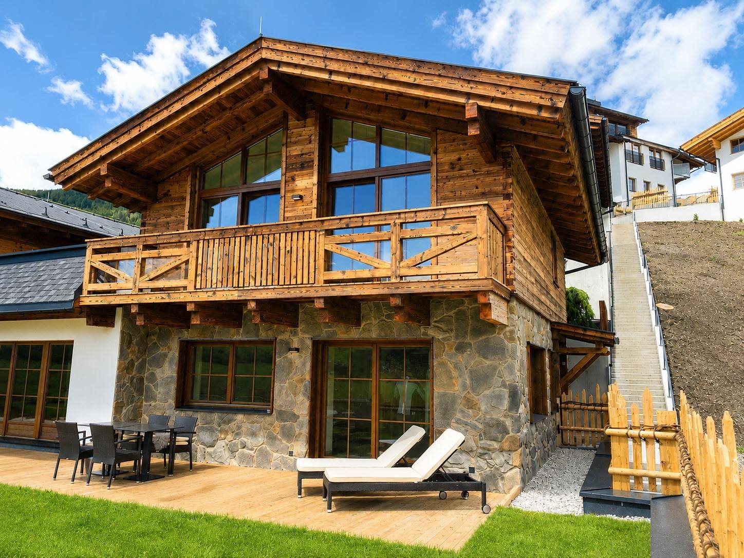 Charmantes Holzchalet mit Steinfassade, großer Terrasse und Balkon in alpiner Umgebung.