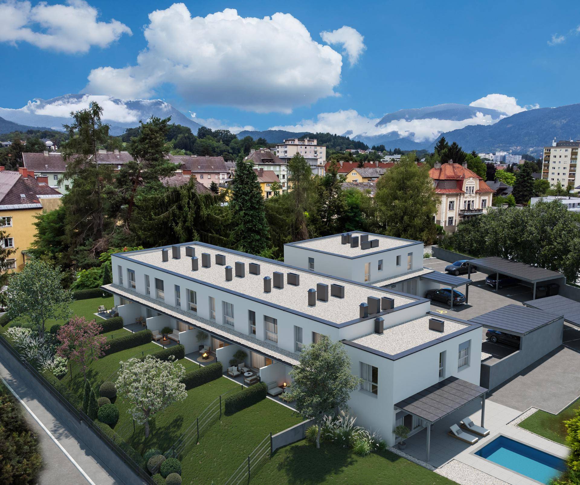 Luftaufnahme einer modernen Wohnanlage mit Reihenhäusern, Gärten, Carports und Gemeinschaftspool.