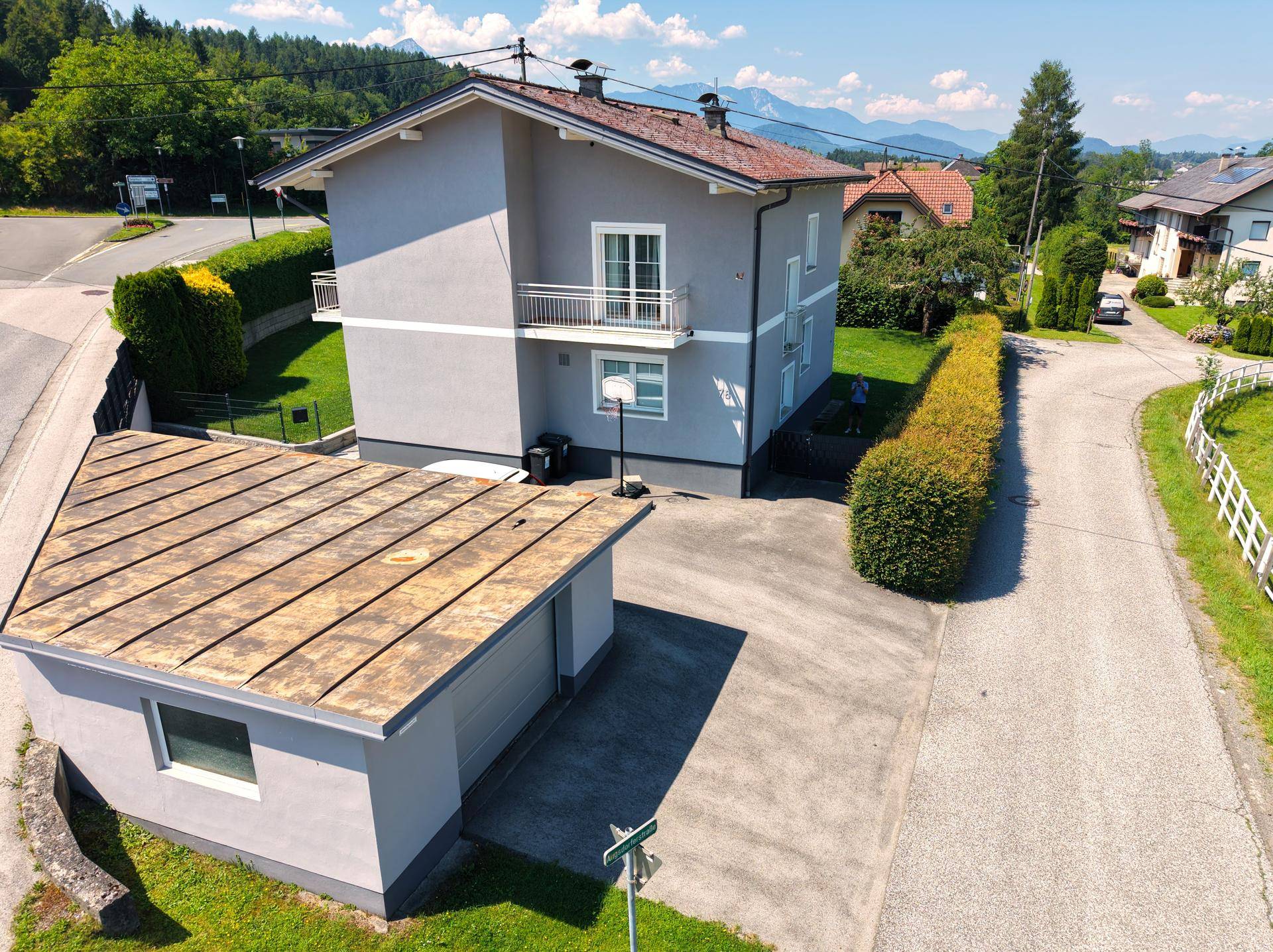 Luftaufnahme des Hauses mit Garage, Auffahrt und Blick auf die umliegenden Berge.