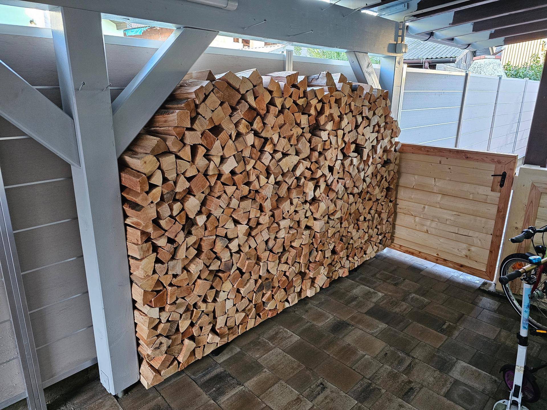 Großer Stapel Brennholz unter einem überdachten Unterstand.