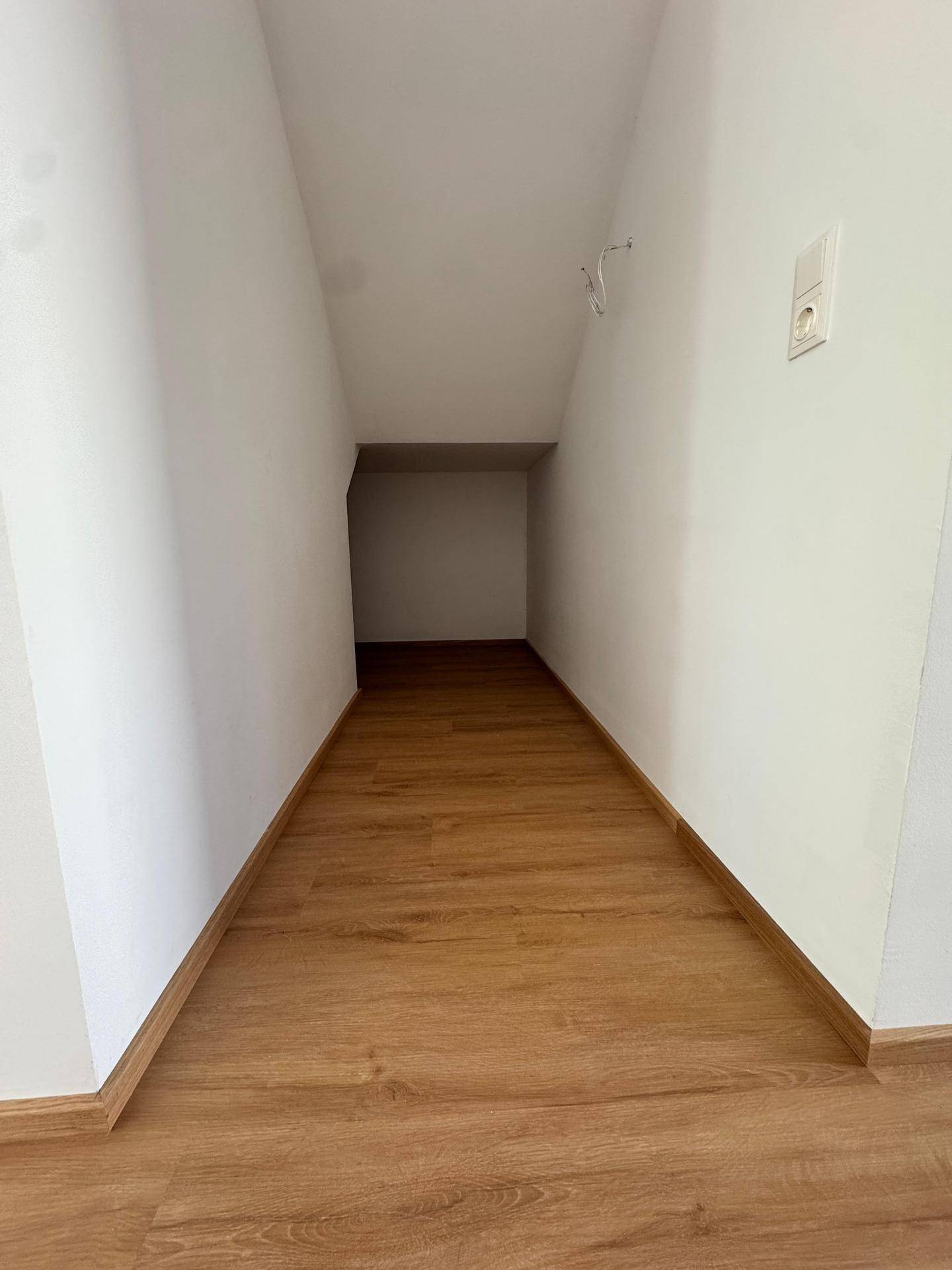 Schmaler Abstellraum mit Laminatboden und weißen Wänden, ideal für zusätzlichen Stauraum.