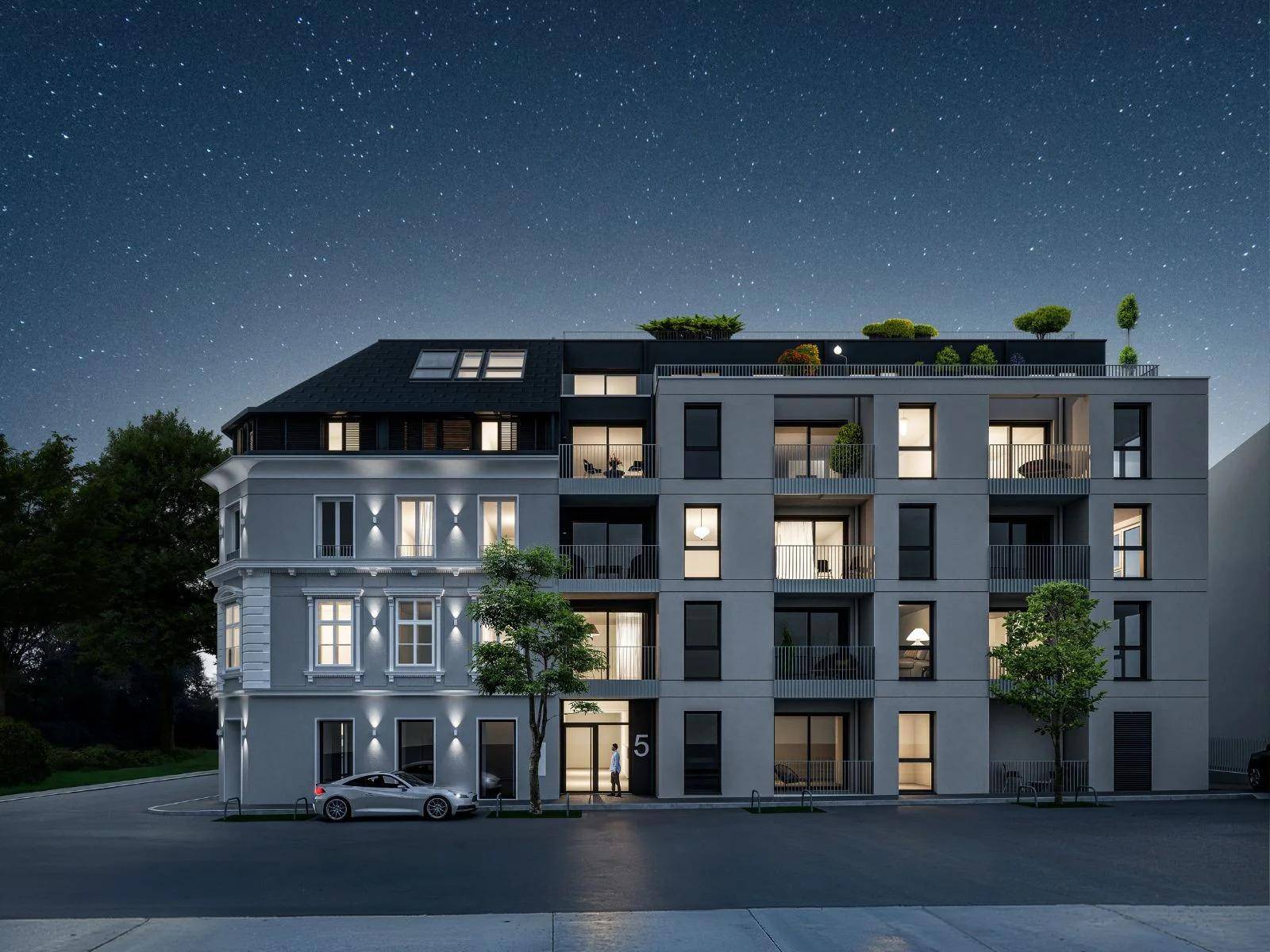 Die moderne Gebäudefassade bei Nacht mit beleuchteten Fenstern und Eingangsbereich.