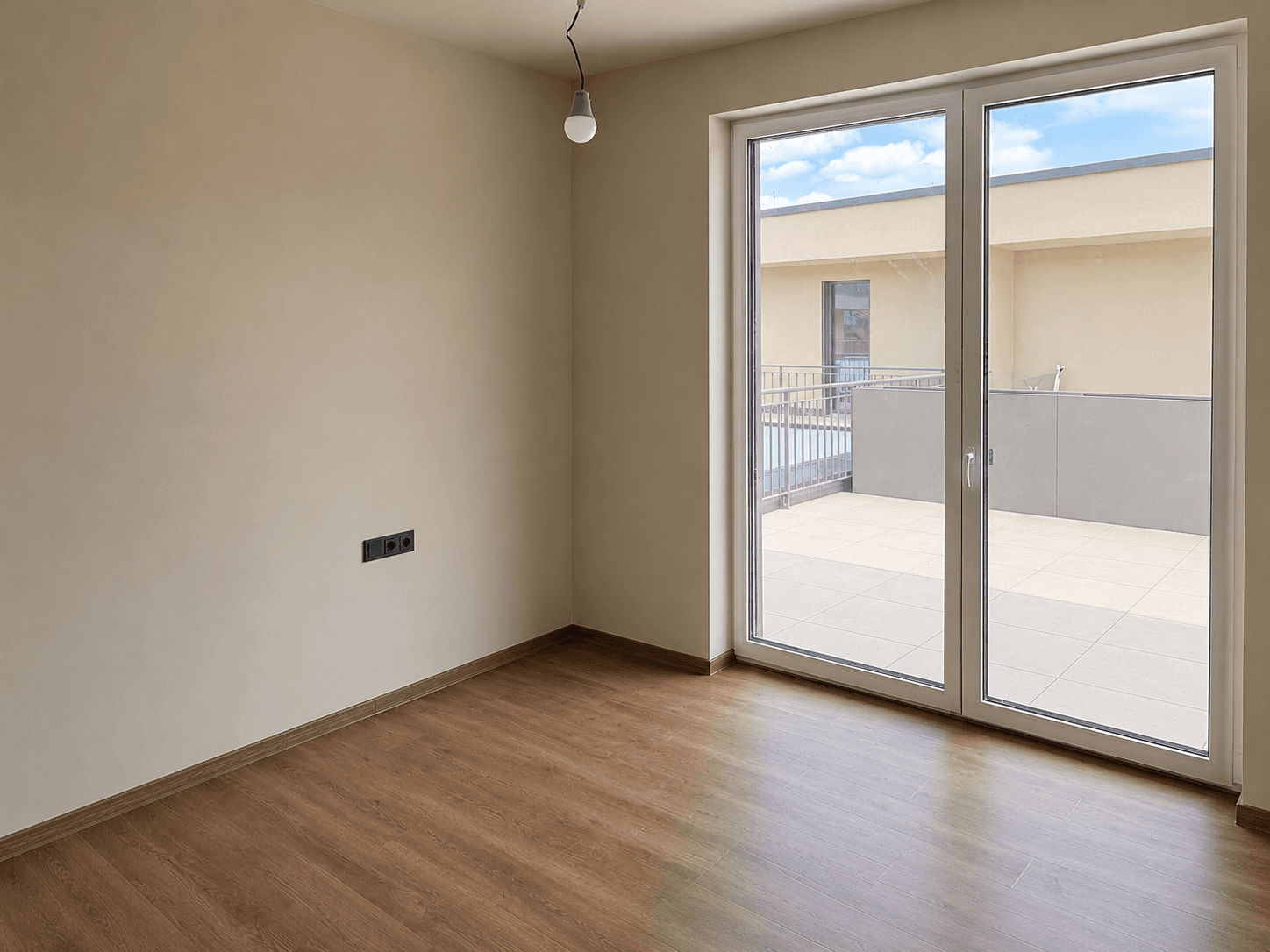 Helles Schlafzimmer mit Laminatboden und Zugang zu einer privaten Terrasse.