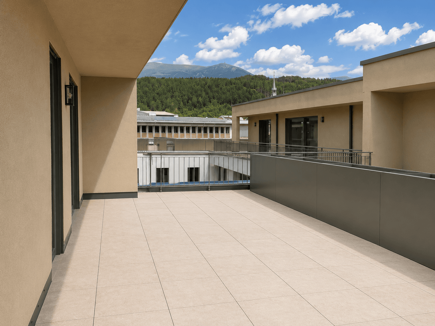 Geräumige Dachterrasse mit Fliesenboden und Blick auf die umliegende Berglandschaft.