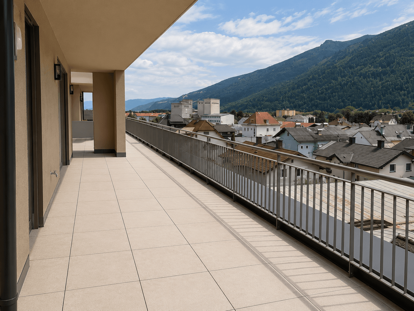 Lange, geflieste Terrasse mit Metallgeländer und weitem Blick über die Stadt und Berge.