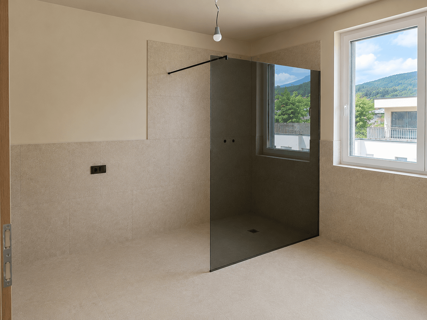Unfertiges Badezimmer mit beigefarbenen Fliesen, einer begehbaren Dusche und Fenster.