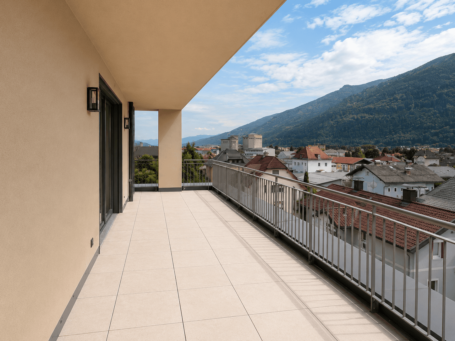 Geräumiger Balkon mit Fliesenboden, Metallgeländer und Panoramablick auf die Stadt und Berge.