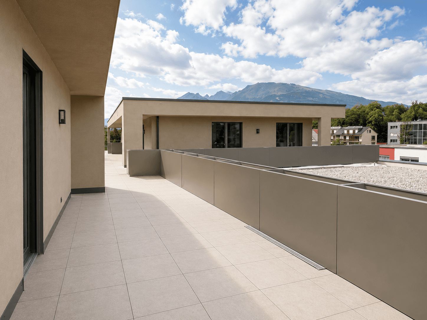 Weitläufige Dachterrasse mit Fliesenboden und beeindruckendem Bergblick unter blauem Himmel.