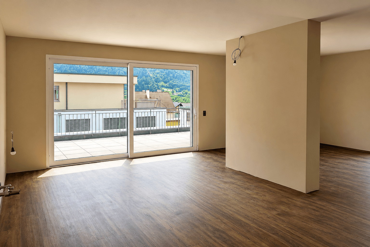 Lichtdurchfluteter Wohnbereich mit Laminatboden und Schiebetüren, die auf eine sonnige Terrasse führen.