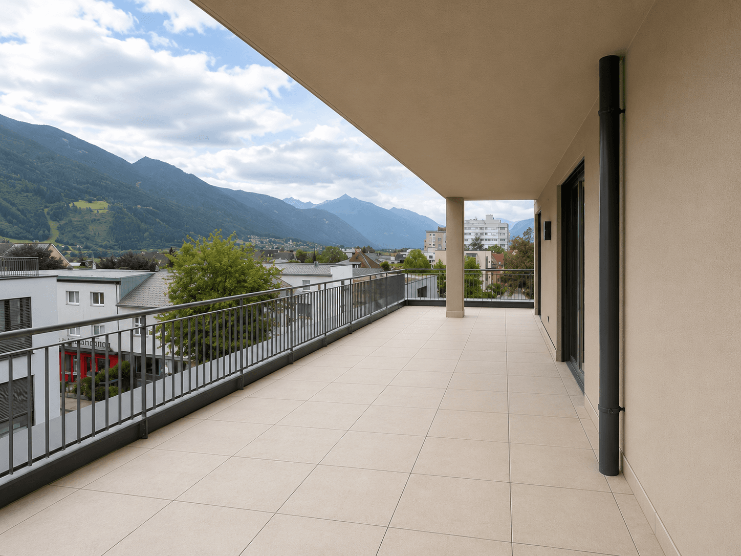 Langer, überdachter Balkon mit Fliesenboden und Panoramablick auf die umliegende Berglandschaft.